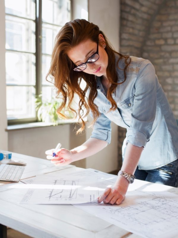 Portrait of young attractive female architect working on project in office