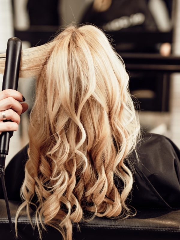 Beautiful hairstyle of blond middle-aged woman in modern hair salon.